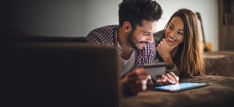 Couple holding credit card in front of laptop