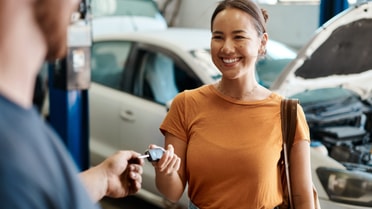 Woman in yellow t shirt receiving keys to new car