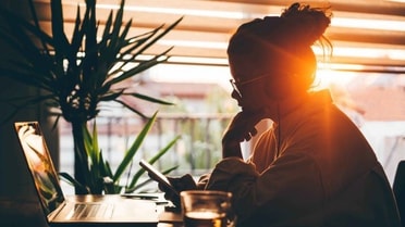 Silhouette girl looking at laptop in the sunset 