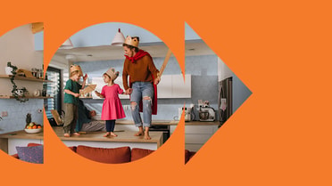 Adult and children wearing cardboard crowns and playing in a kitchen.