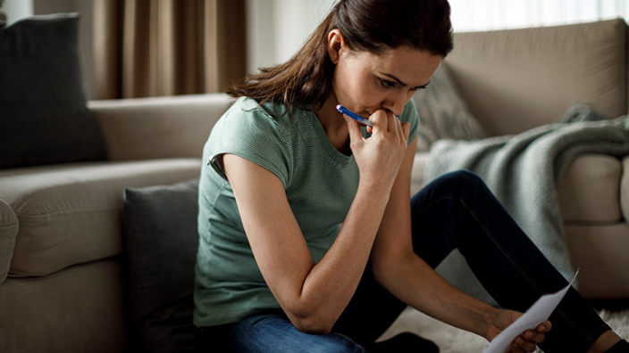 Women on phone with piece of paper concerned