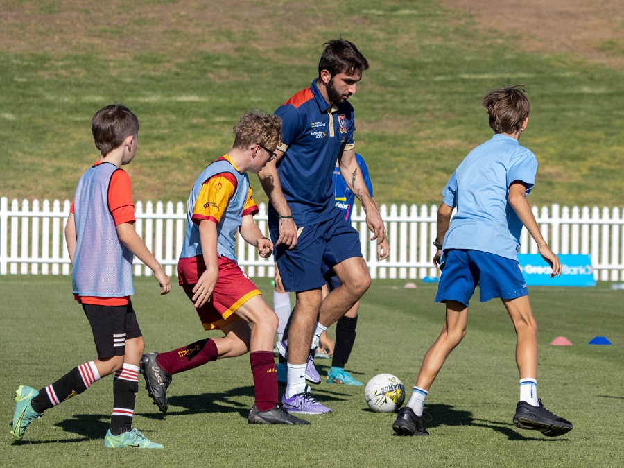 Jets player kicking ball in group of kids