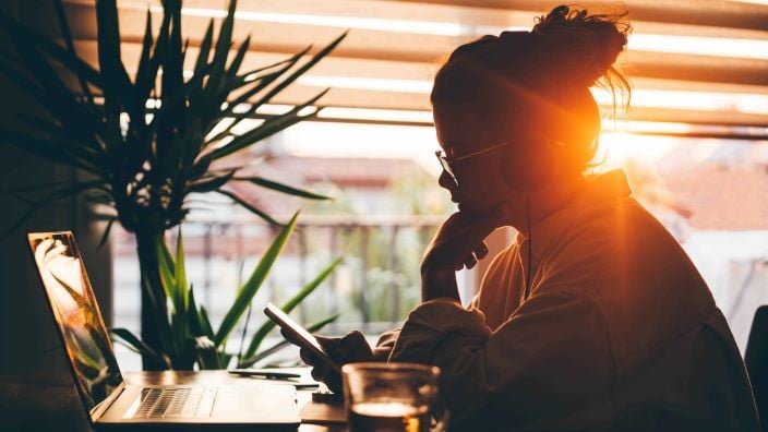 Girl looking at laptop in sunset