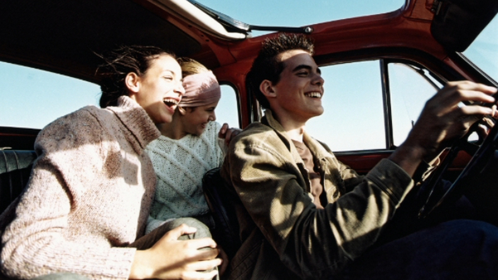 Friends in car on a holiday laughing while site seeing