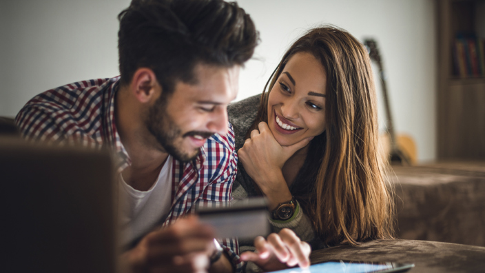 Couple holding credit card in front of laptop